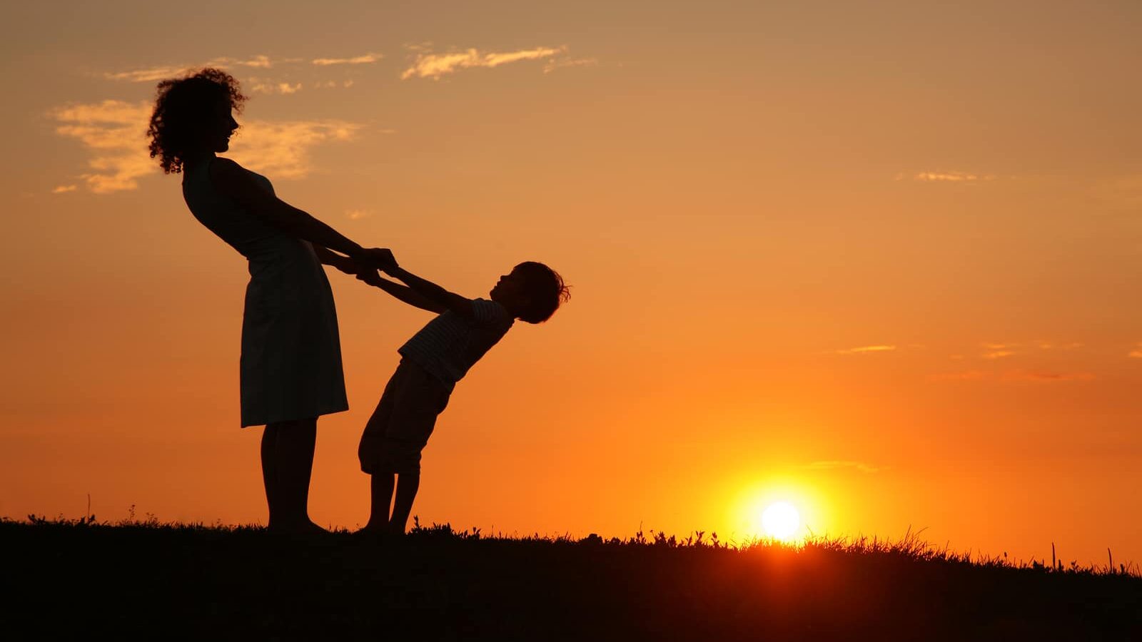 Mother and son on sunset holding by hands