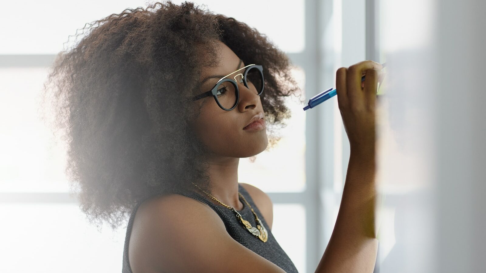 Friendly african american executive business woman brainstorming using green adhesive notes in a modern white office