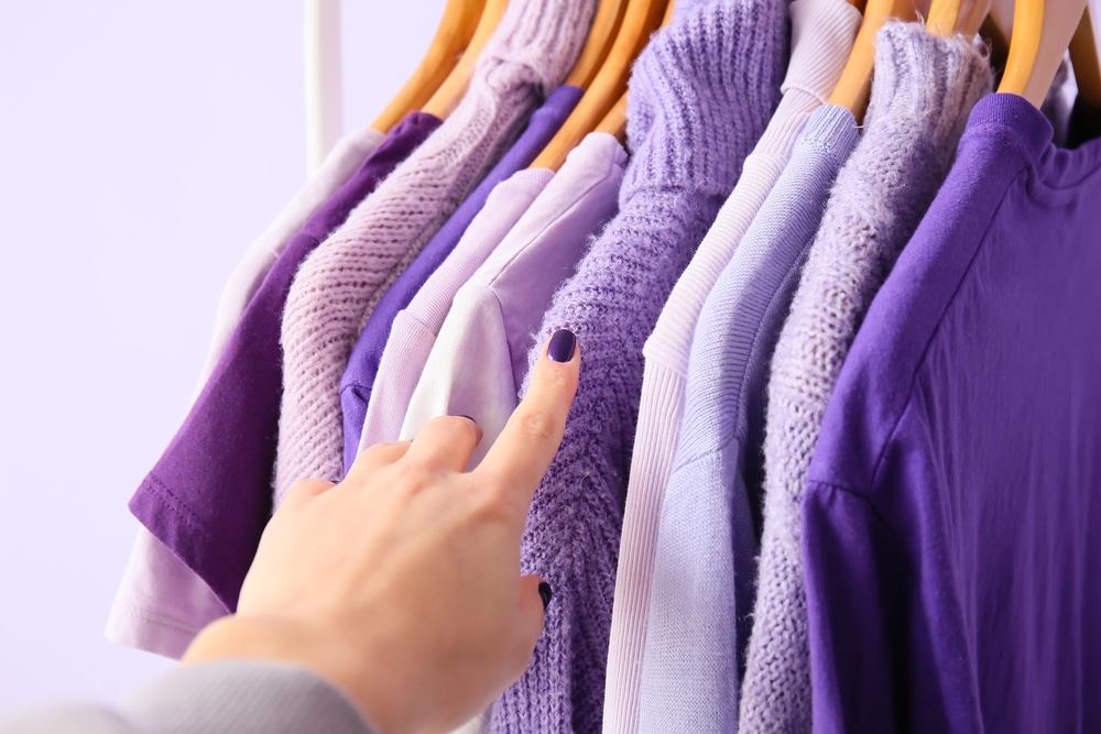 Dedo feminino apontando roupas de cor lilás.
