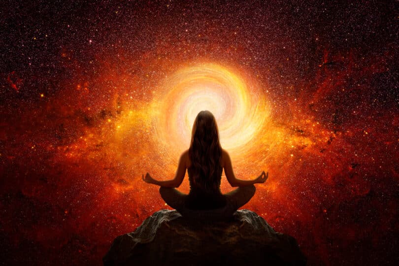 Silhueta de mulher meditando em frente a um buraco de luz laranja e vermelha
