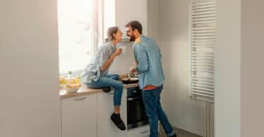 Imagem de um casal tomando café da manhã e sorrindo, animados