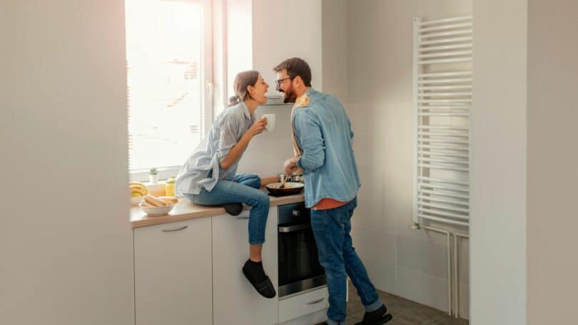 Imagem de um casal tomando café da manhã e sorrindo, animados