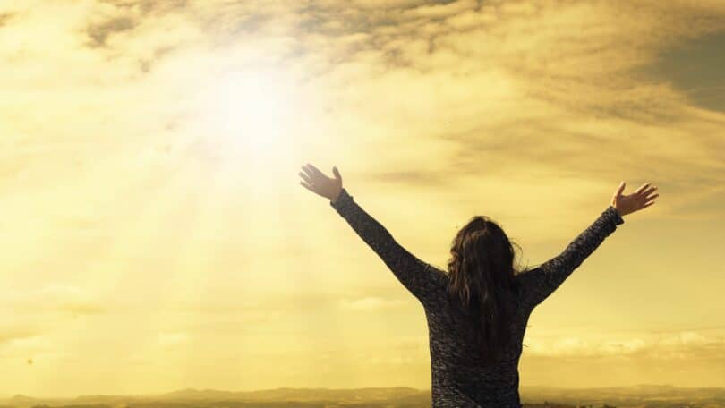 Imagem de uma mulher com os braços erguidos para o céu