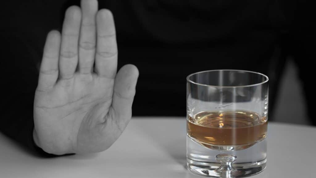 Imagem de uma pessoa recusando um copo de bebida alcoólica