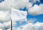Bandeira branca hasteada no céu azul com algumas nuvens