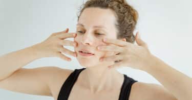 Mulher fazendo massagem facial em si mesma com a ponta dos dedos