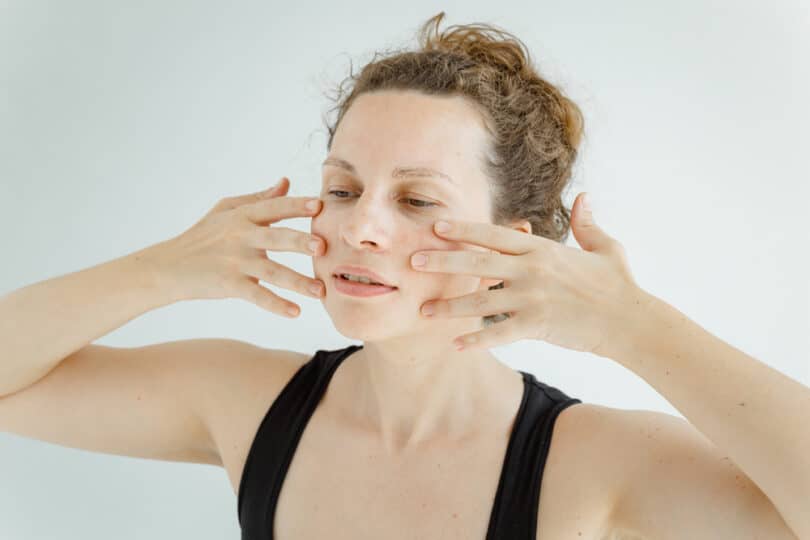 Mulher fazendo massagem facial em si mesma com a ponta dos dedos