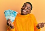 Mulher segurando várias notas de dinheiro e sorrindo