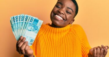 Mulher segurando várias notas de dinheiro e sorrindo