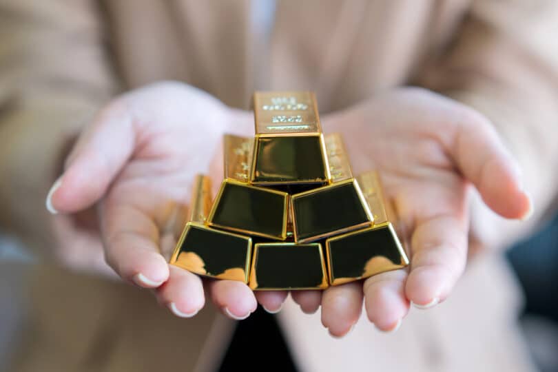 Seis barras de ouro nas mãos de uma mulher