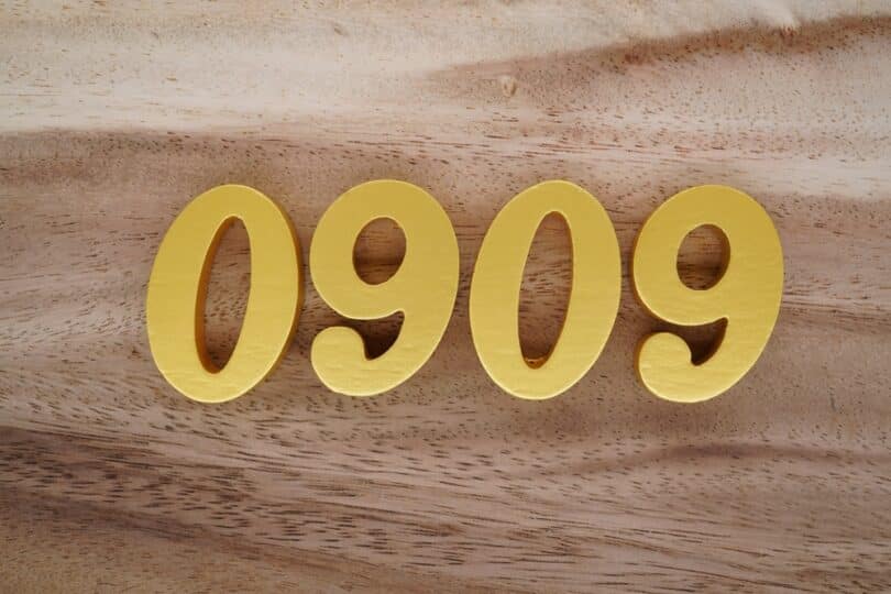 Número 0909 dourado sobre superfície de madeira