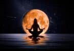 Silhueta de mulher sentada meditando sobre as águas com uma grande Lua dourada ao seu redor