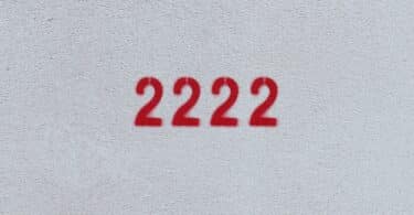 Número 2222 estampado de vermelho em parede branca