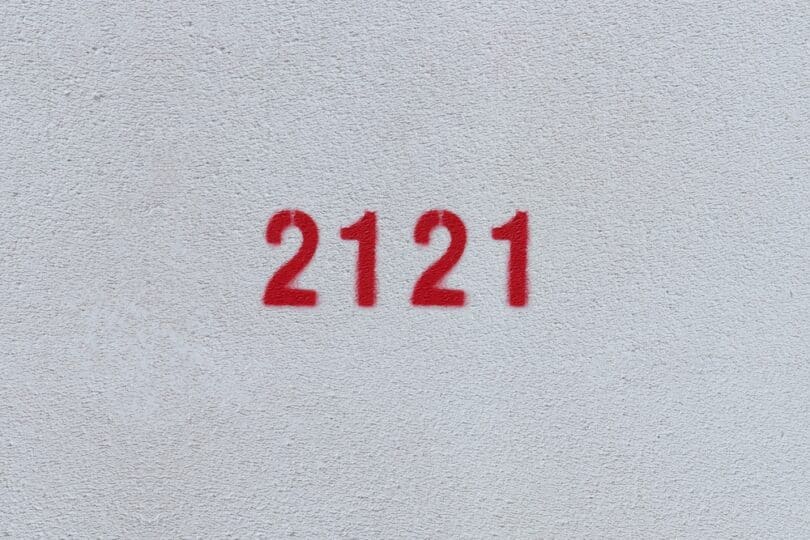 Número 2121 estampado de vermelho numa parede branca