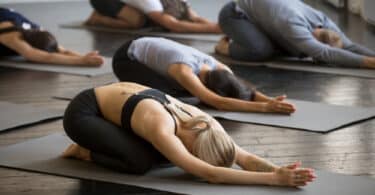 Várias pessoas numa sala fazendo Yoga em conjunto