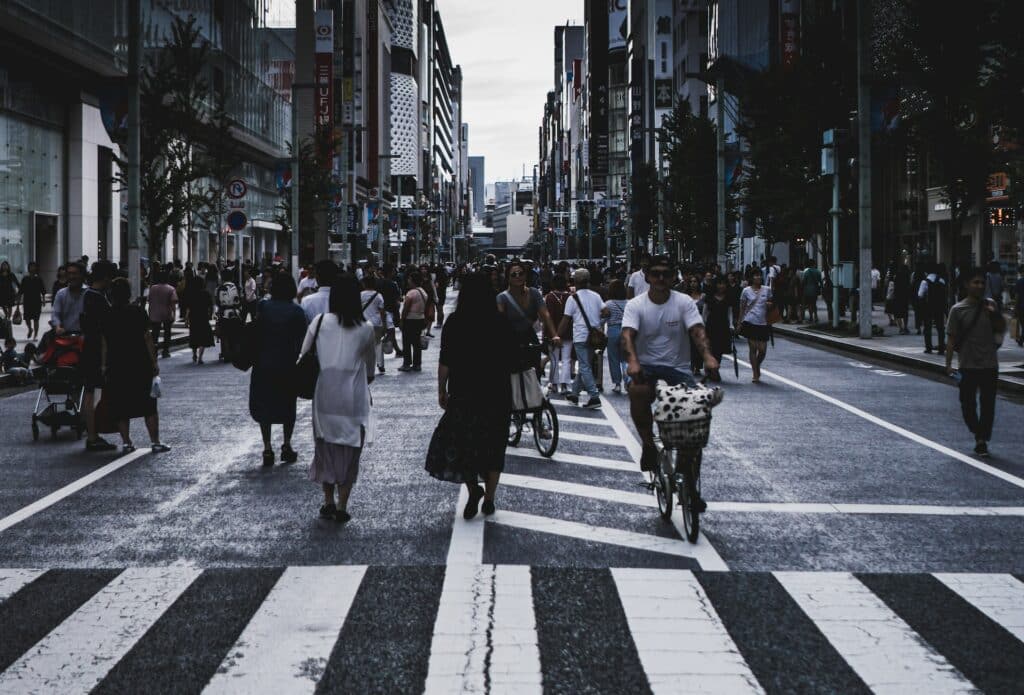 Várias pessoas desconhecidas caminhando na rua movimentada de uma cidade.