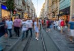 Várias pessoas desconhecidas caminhando na rua durante o dia. A maioria está desfocada.