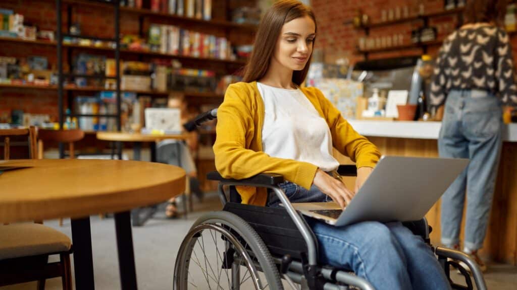 Imagem de uma mulher de cadeira de rodas com um notebook no colo