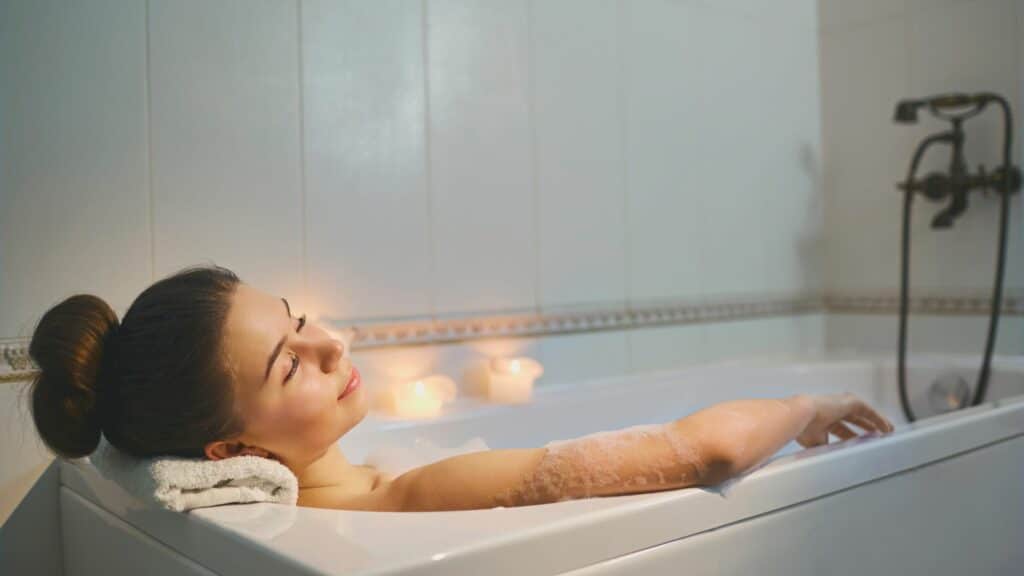 Imagem de uma mulher tomando banho de banheira, com os olhos fechados 