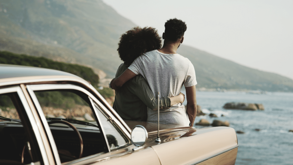 Casal se abraçando em frente a um mar