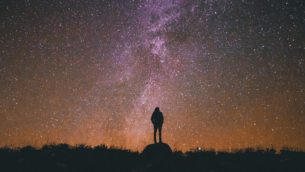 Silhueta de uma pessoa sob o céu estrelado