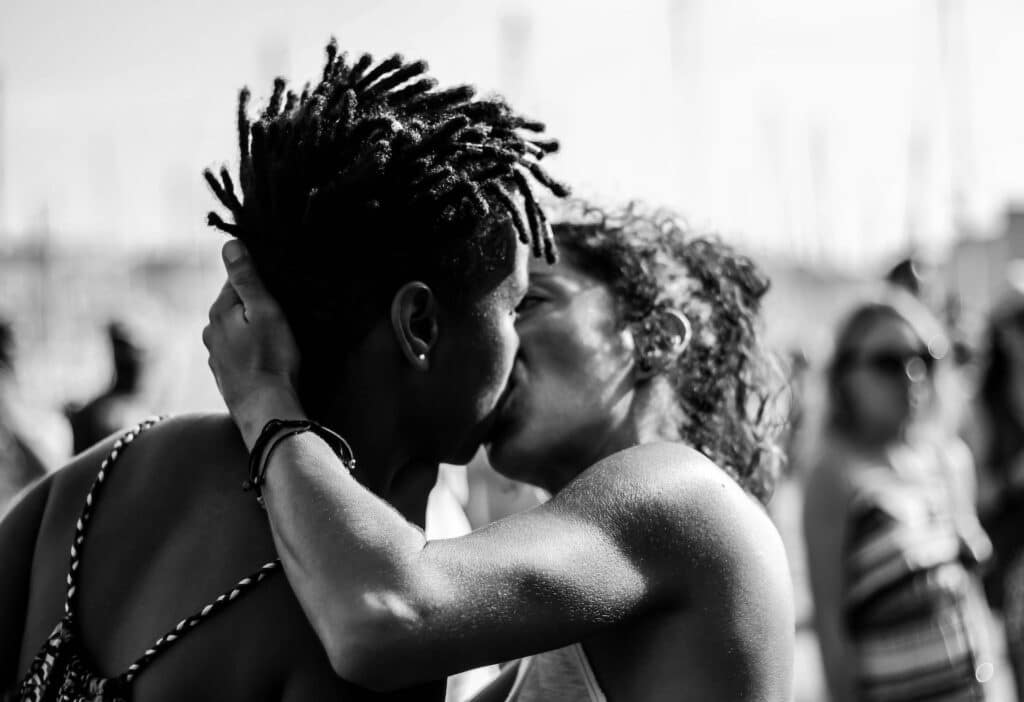Mulheres se beijando em meio a uma multidão.
