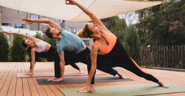 Três pessoas fazendo Yoga juntos ao ar livre, num deck