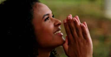 Mulher com expressão de gratidão e serenidade orando e olhando para cima