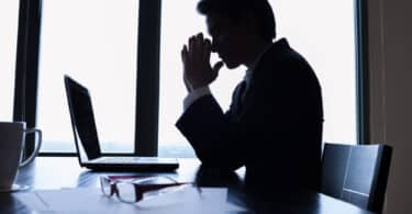 Homem rezando em sua mesa de trabalho