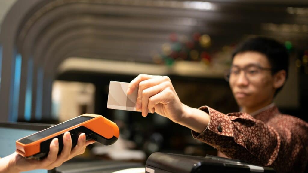 Imagem de um homem passando o cartão em uma maquininha