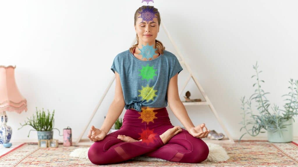 Imagem de uma mulher com a postura de lótus do Yoga e ilustrados a frente dela seus chakras