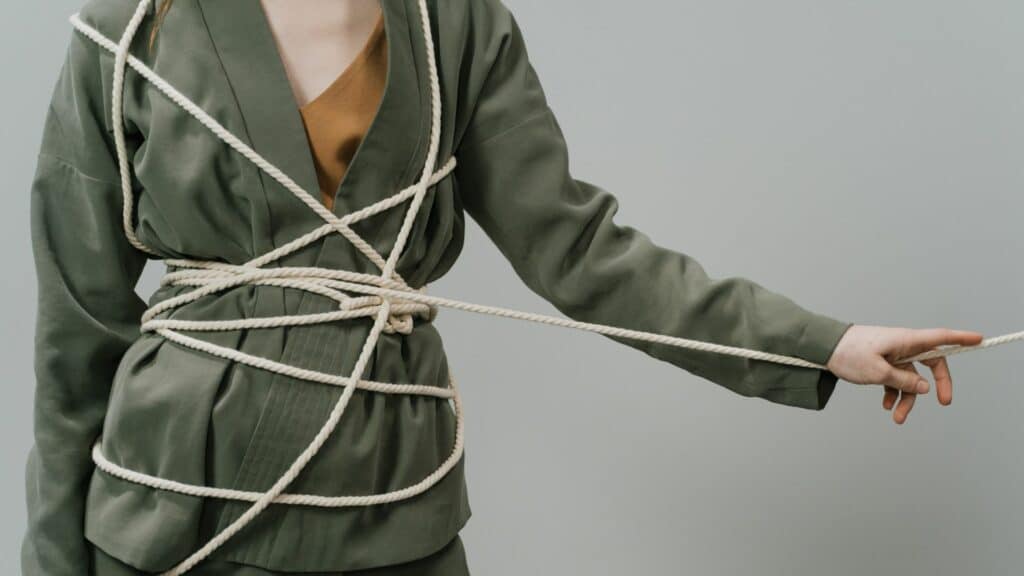 Imagem de uma mulher que está presa e embaraçada em uma corda