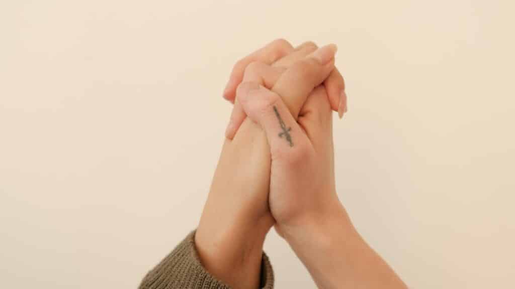 Imagem de duas mãos entrelaçadas em um fundo cor de creme