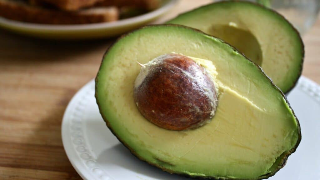 Imagem de uma abacate cortado em cima de um prato na mesa