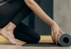 Imagem só das pernas de uma mulher estendendo o tapete de Yoga