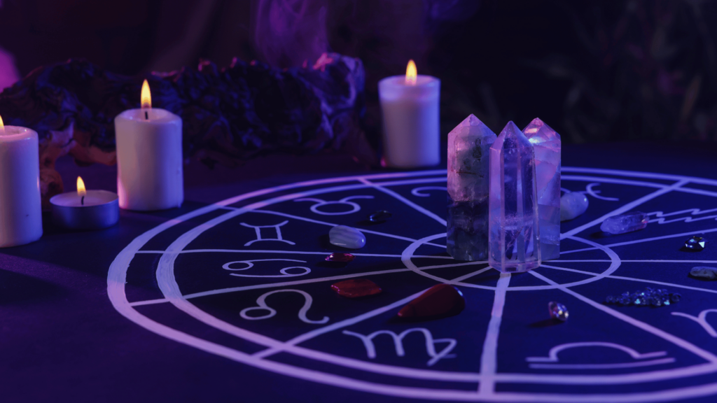 Mesa com velas acesas, cristais e mesa com signos