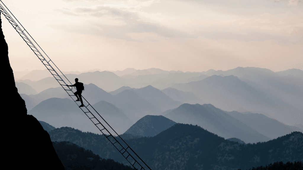 Pessoa subindo uma escada inclinada em meio a muitas montanhas