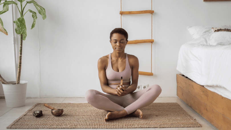 Mulher negra sentada em posição de yoga