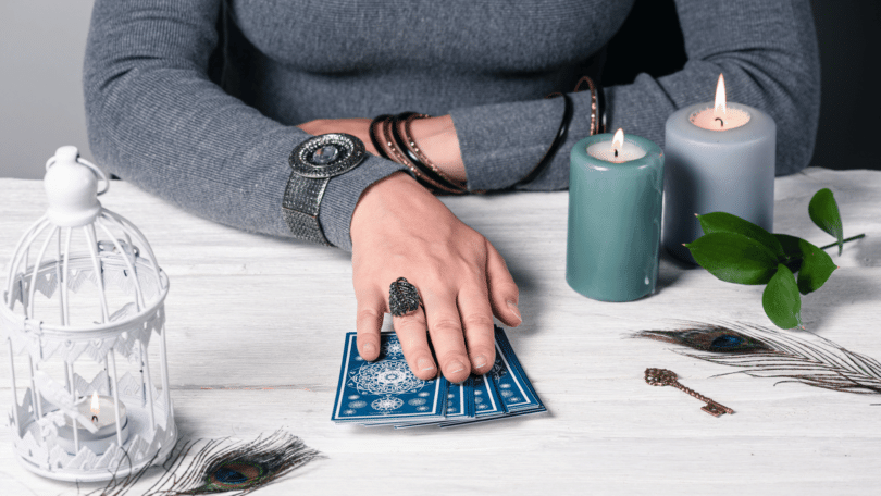 Mulher sentada com cartas de tarot, velas e outras coisas