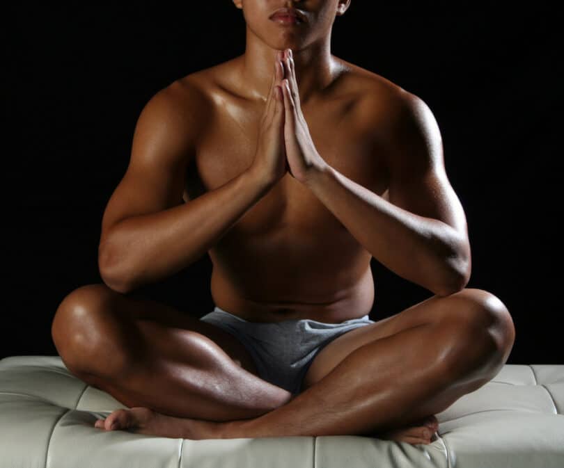 Homem concentrado fazendo Yoga em posição sentada no chão