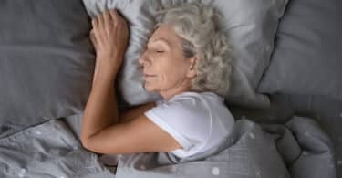 Vista de cima de uma mulher idosa dormindo calmamente em sua cama