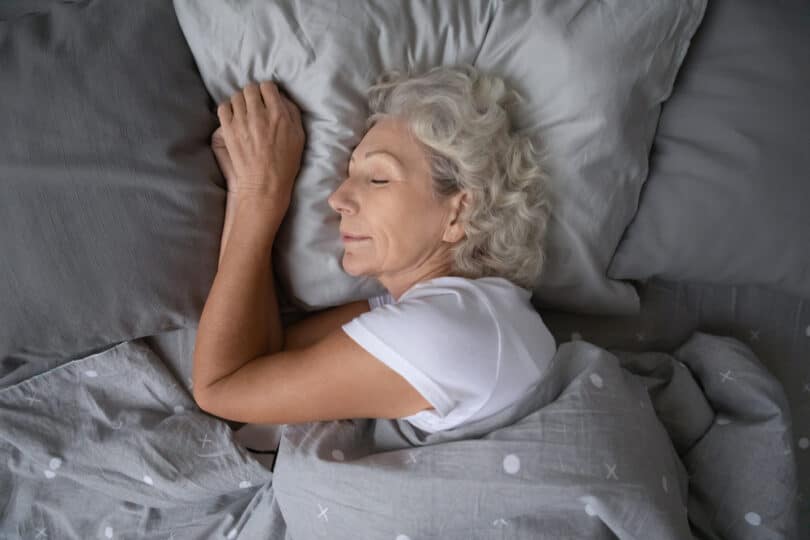 Vista de cima de uma mulher idosa dormindo calmamente em sua cama