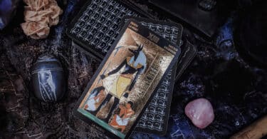 Carta de tarot egípcio sobre uma mesa cheia de cristais e itens egípcios
