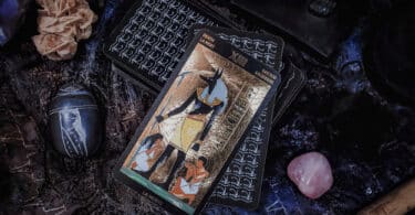 Carta de tarot egípcio sobre uma mesa cheia de cristais e itens egípcios