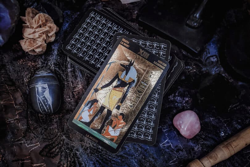 Carta de tarot egípcio sobre uma mesa cheia de cristais e itens egípcios