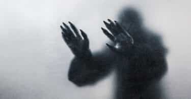 Sombra de um monstro colocando as mãos em um vidro
