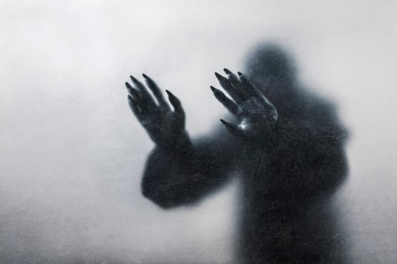 Sombra de um monstro colocando as mãos em um vidro