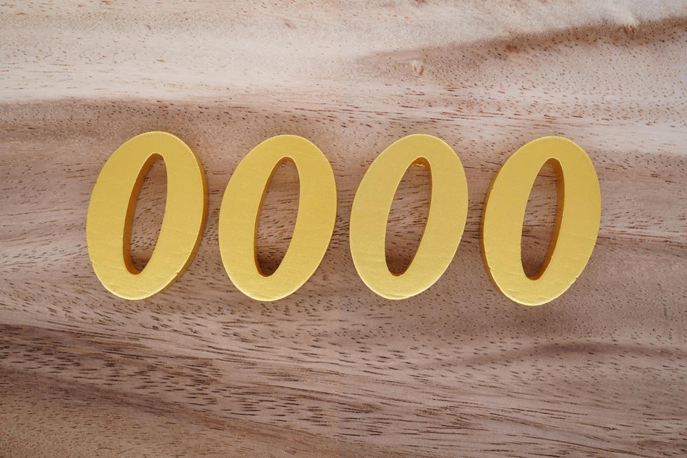 Número 0000 em algarismos dourados sobre superfície de madeira