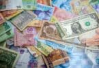 Notas de dinheiro espalhadas em uma superfície e sobrepostas, em uma variedade de cores, simbolizando sonhar com notas de dinheiro.