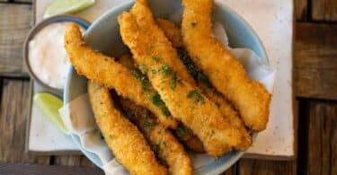 Prato com tiras de tilápia frita, simbolizando sonhar com peixe frito.